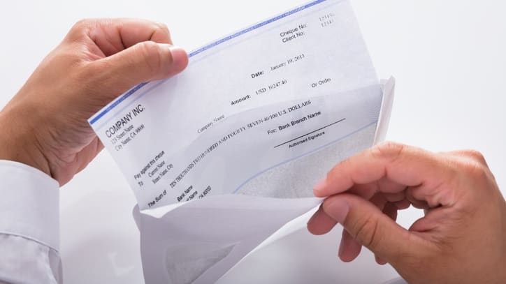 A man is holding a check in front of a white background.
