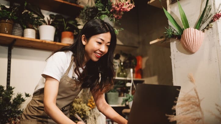 Asian florist working on her laptop in a flower shop.