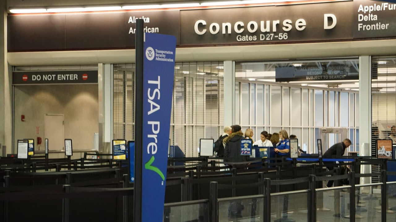 A group of people standing at the entrance of an airport.