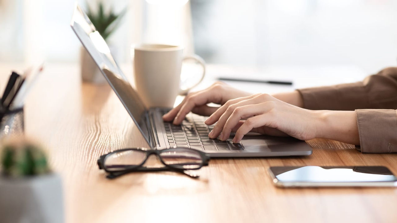 A woman typing on a laptop at a desk.