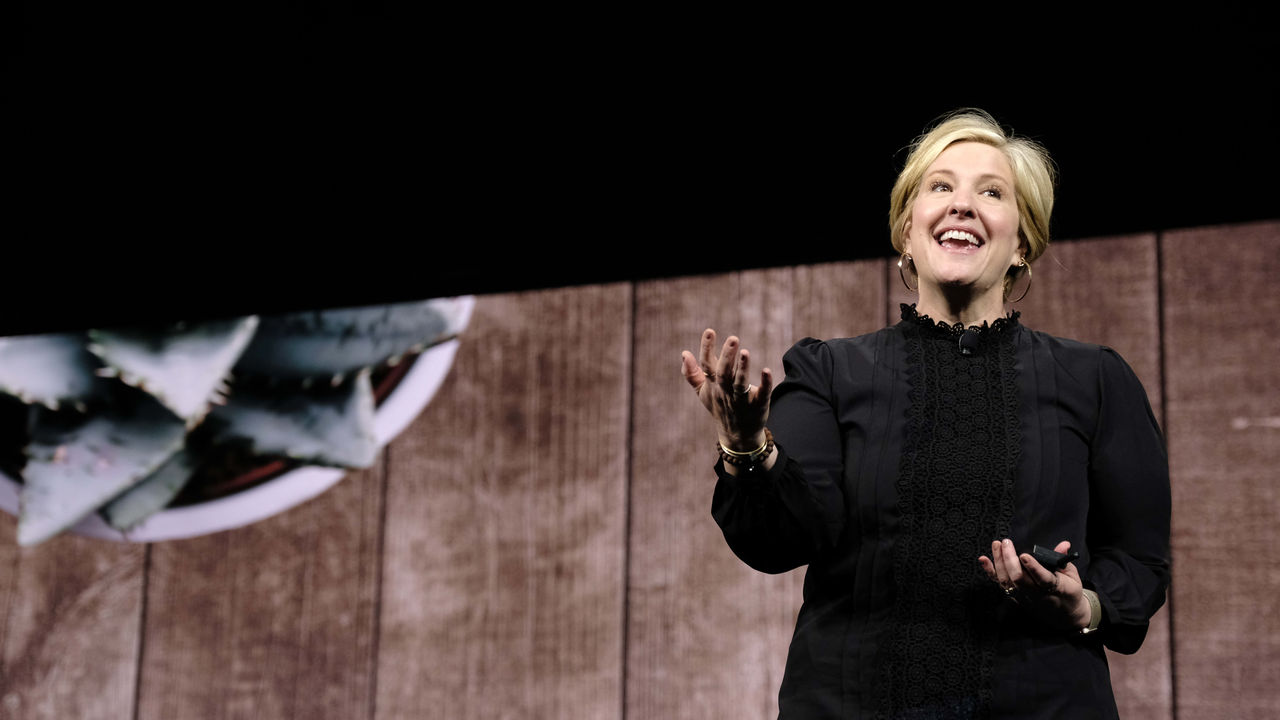 A woman is standing on stage with a plant in front of her.