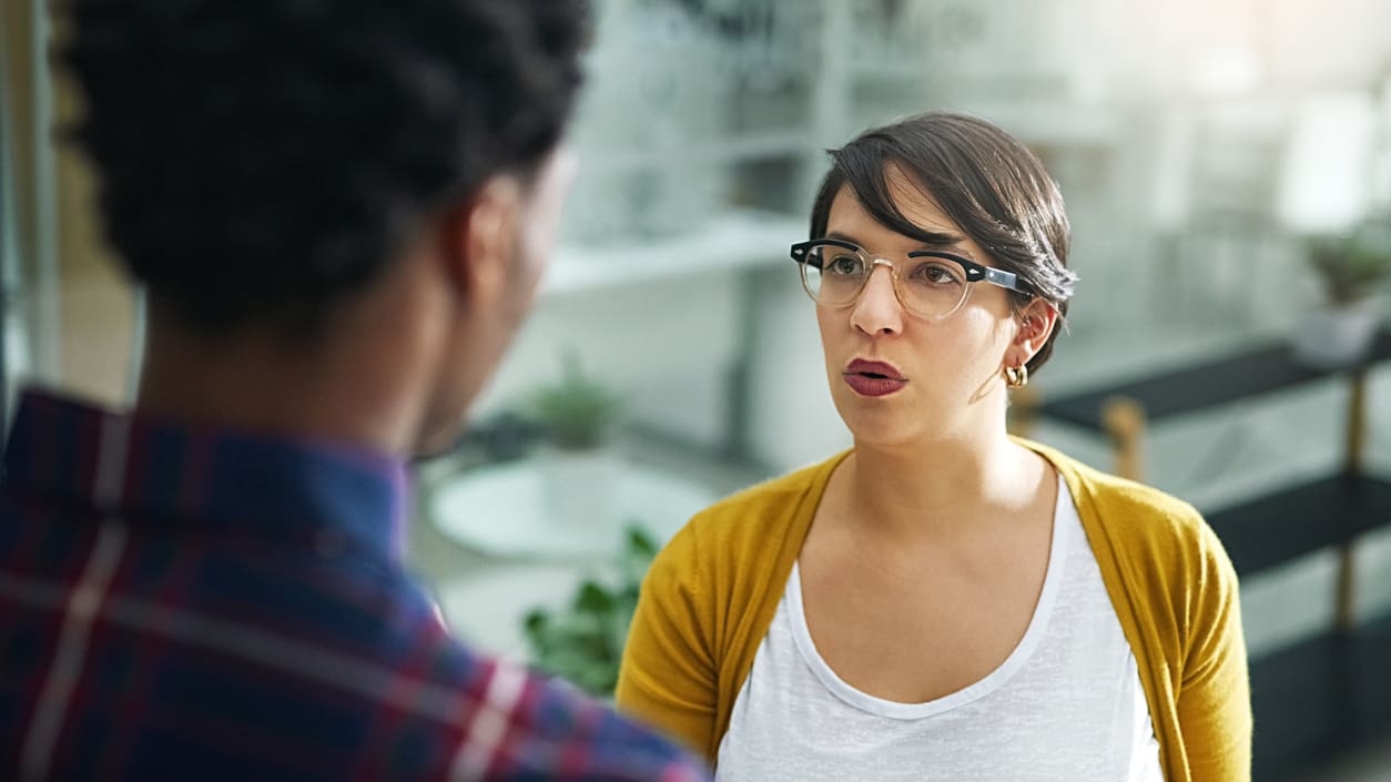 A woman is talking to a man in an office.