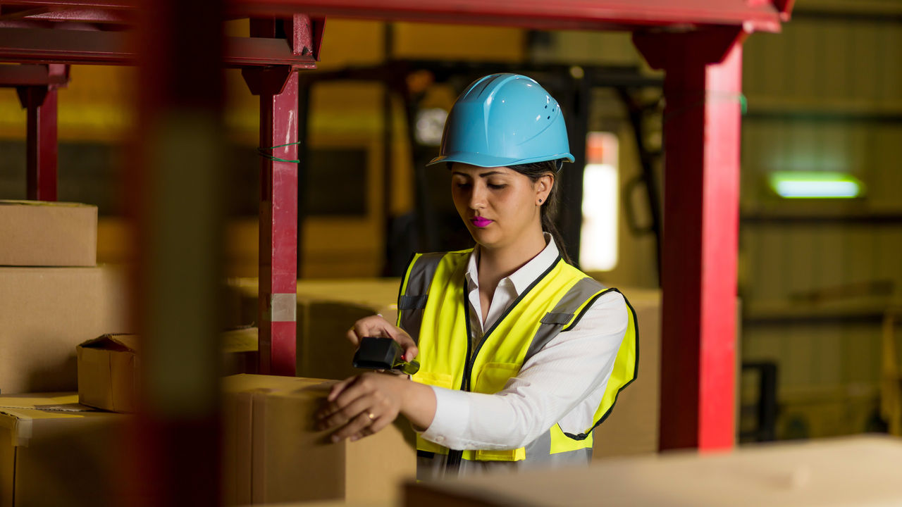 A woman in a hard hat working in a warehouse.