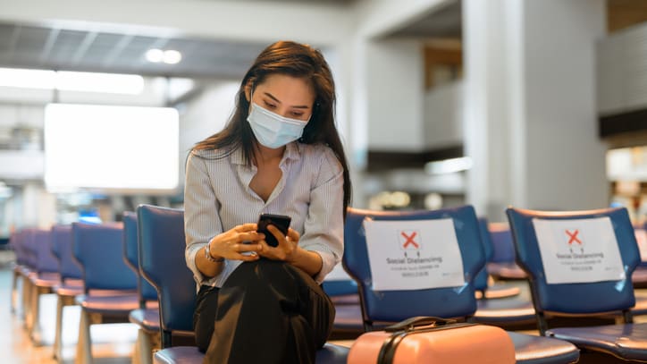 A woman wearing a face mask sitting in an airport.