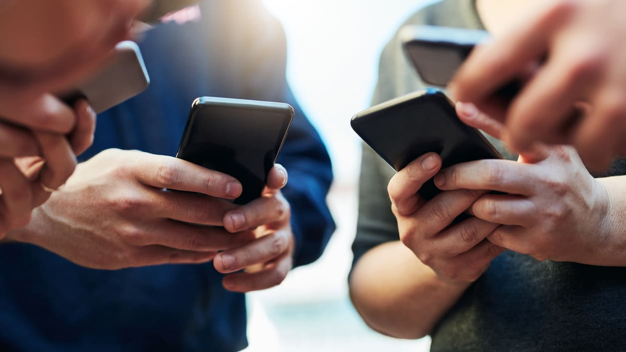 A group of people holding cell phones in their hands.