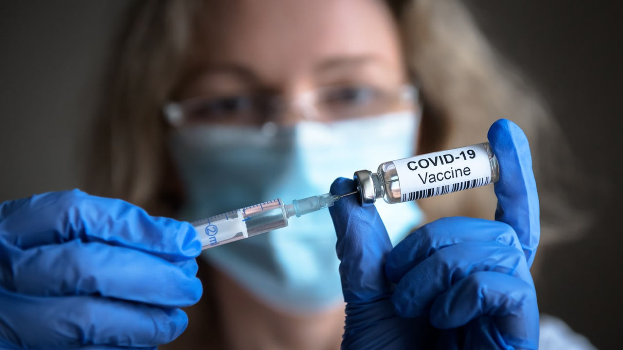 A woman is holding a syringe of coronavirus vaccine.