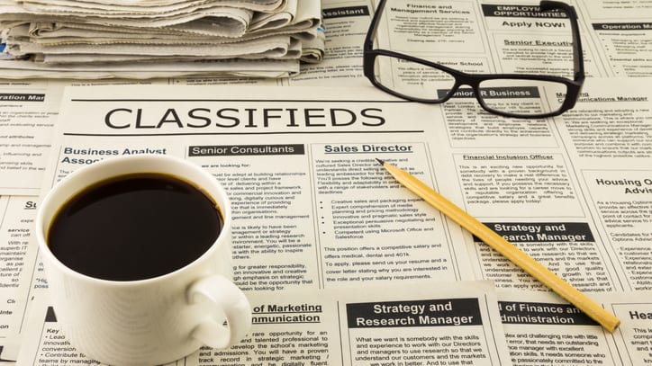 A cup of coffee and a newspaper with the word classifieds.