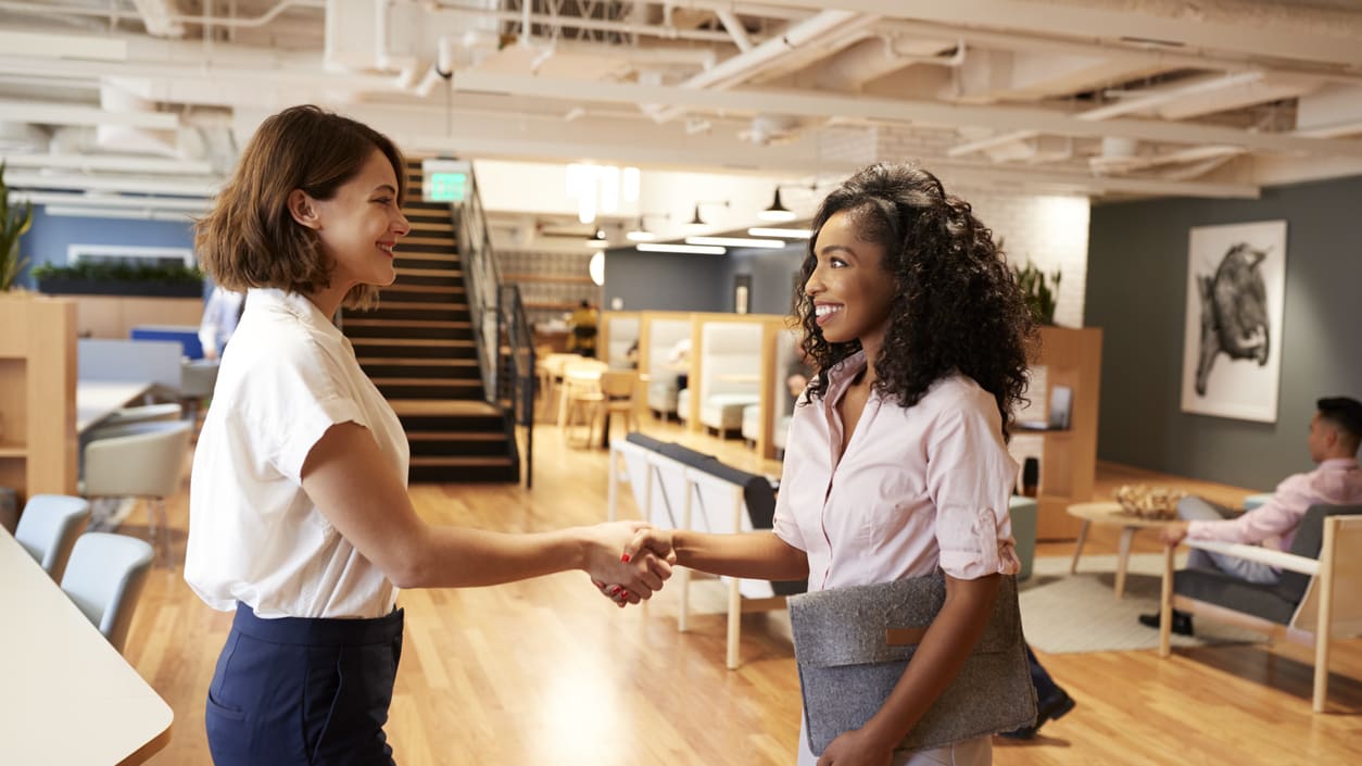 Two business women shaking hands in an office.