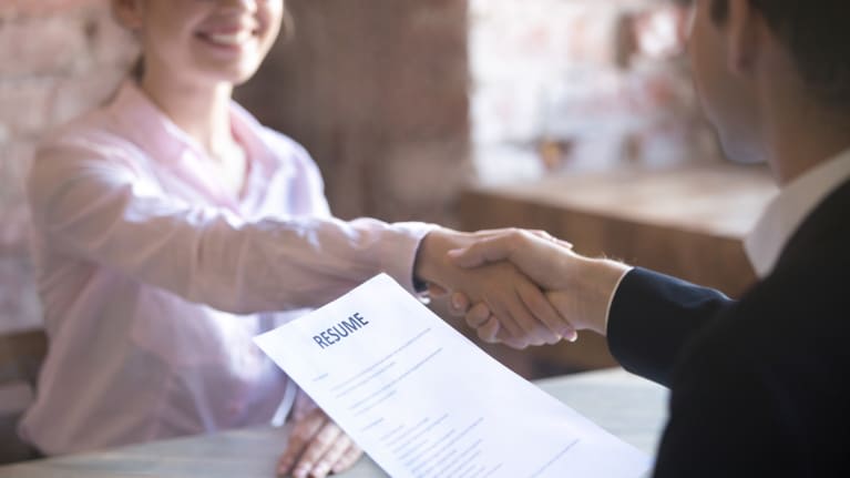 A man shaking hands with a woman over a resume.