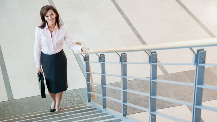 A business woman walking up stairs with a briefcase.