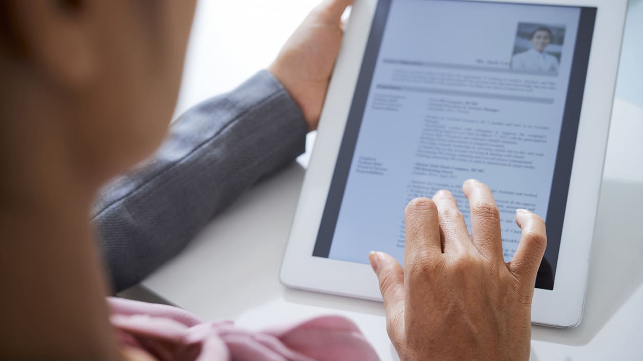 A woman is using a tablet to look at a resume.