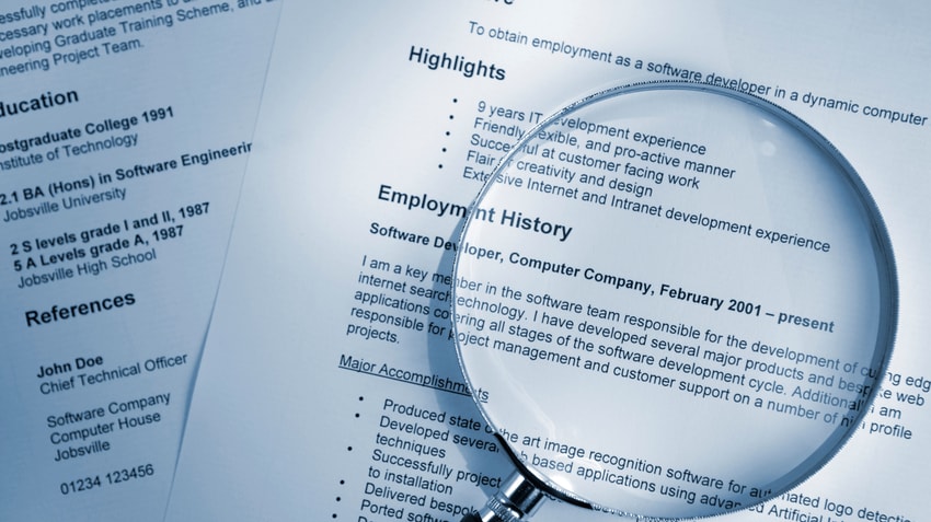 A magnifying glass is placed on top of a resume.