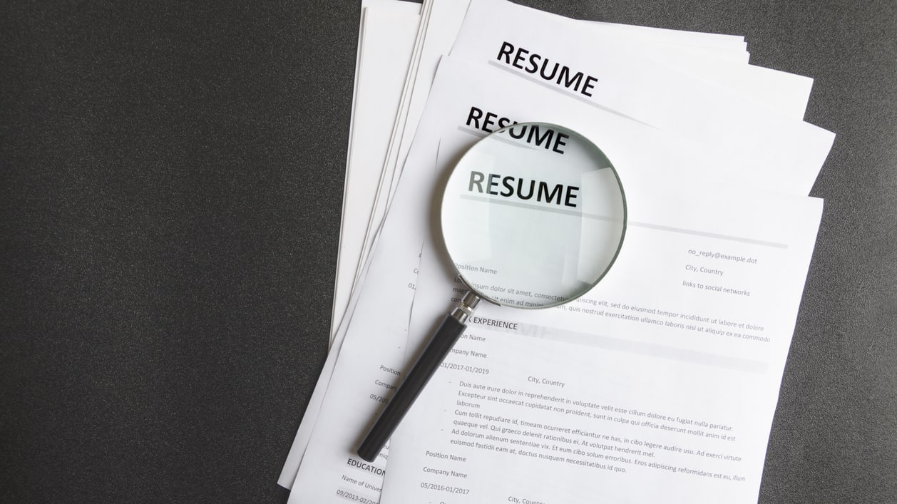 A magnifying glass is placed on top of a resume.