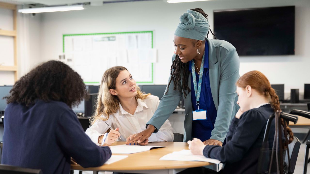 A group of women sitting around a table in a classroom.