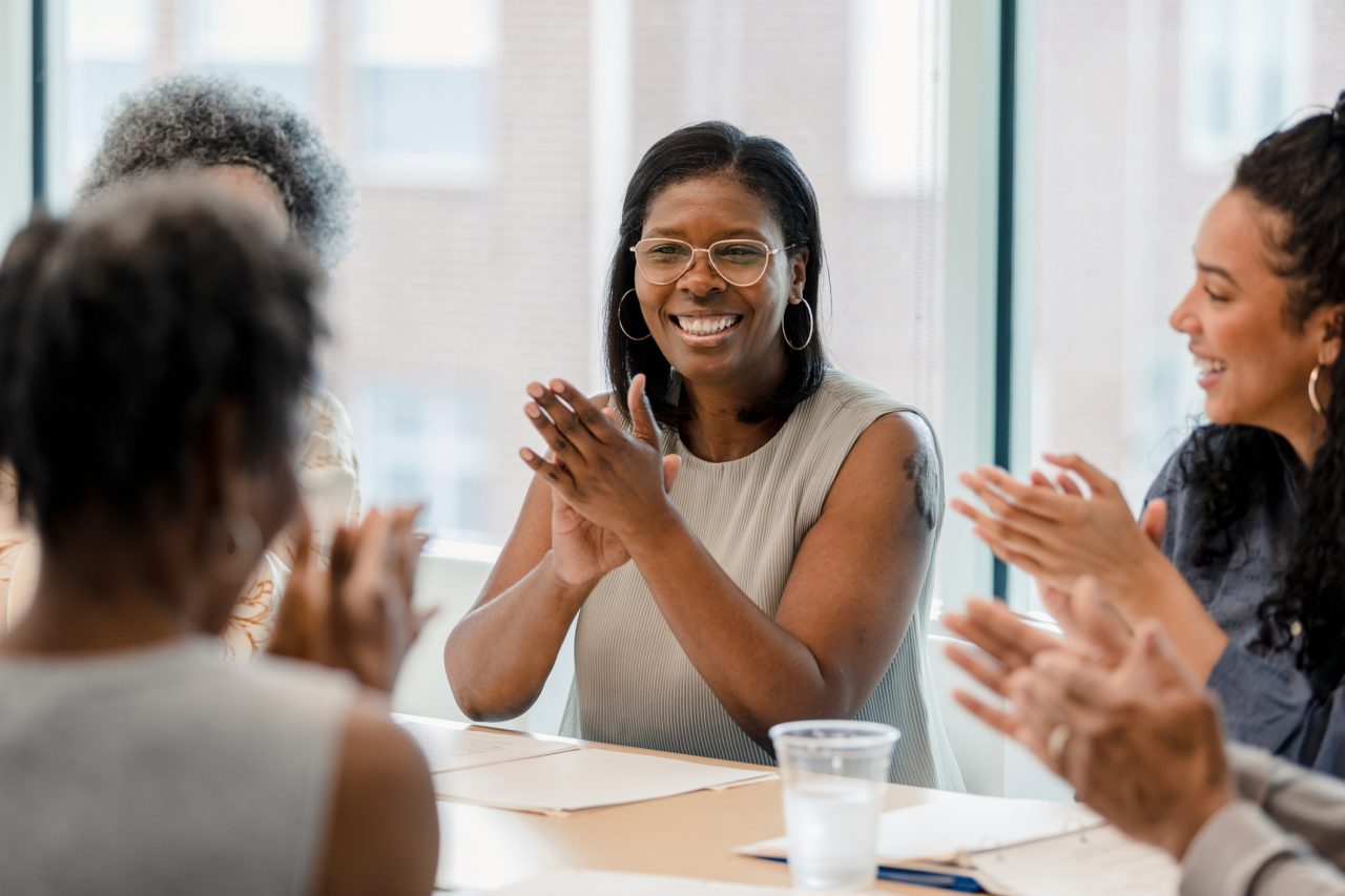 A group of women employees smiling and applauding. 