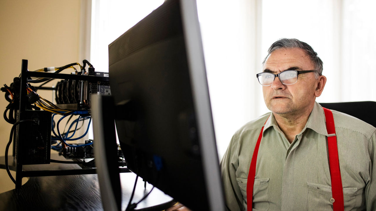 A man wearing glasses is sitting in front of a computer.