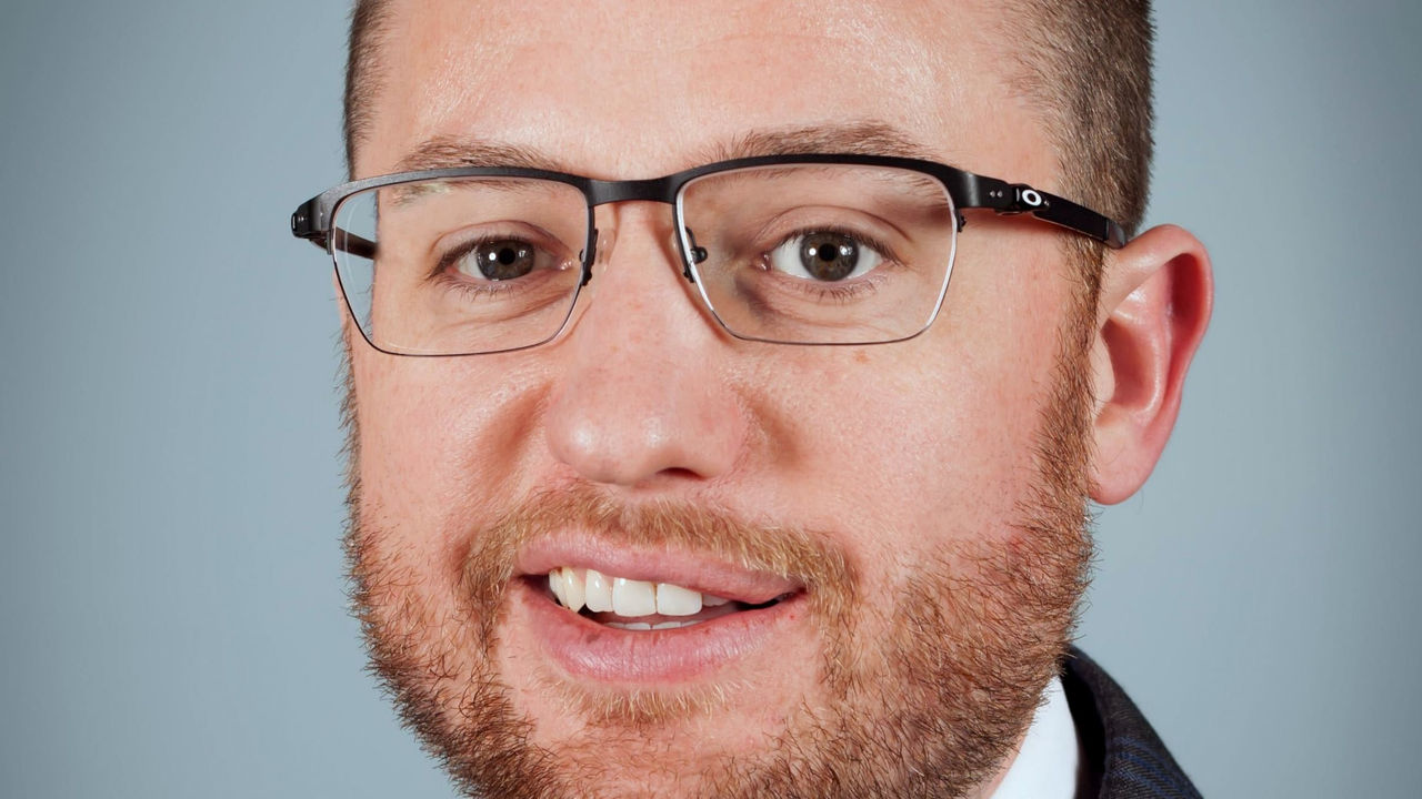 A portrait of a man wearing glasses and a tie.