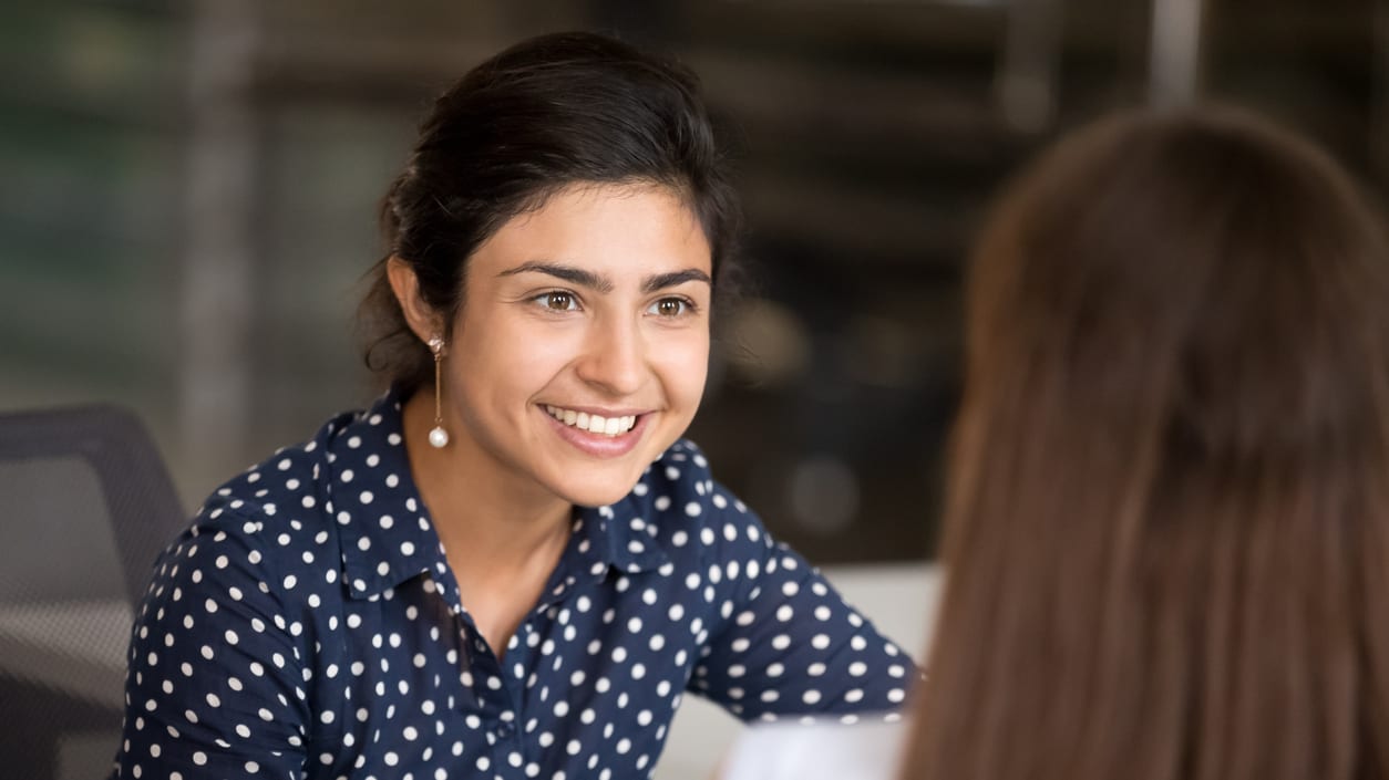 A woman is talking to another woman in an office.