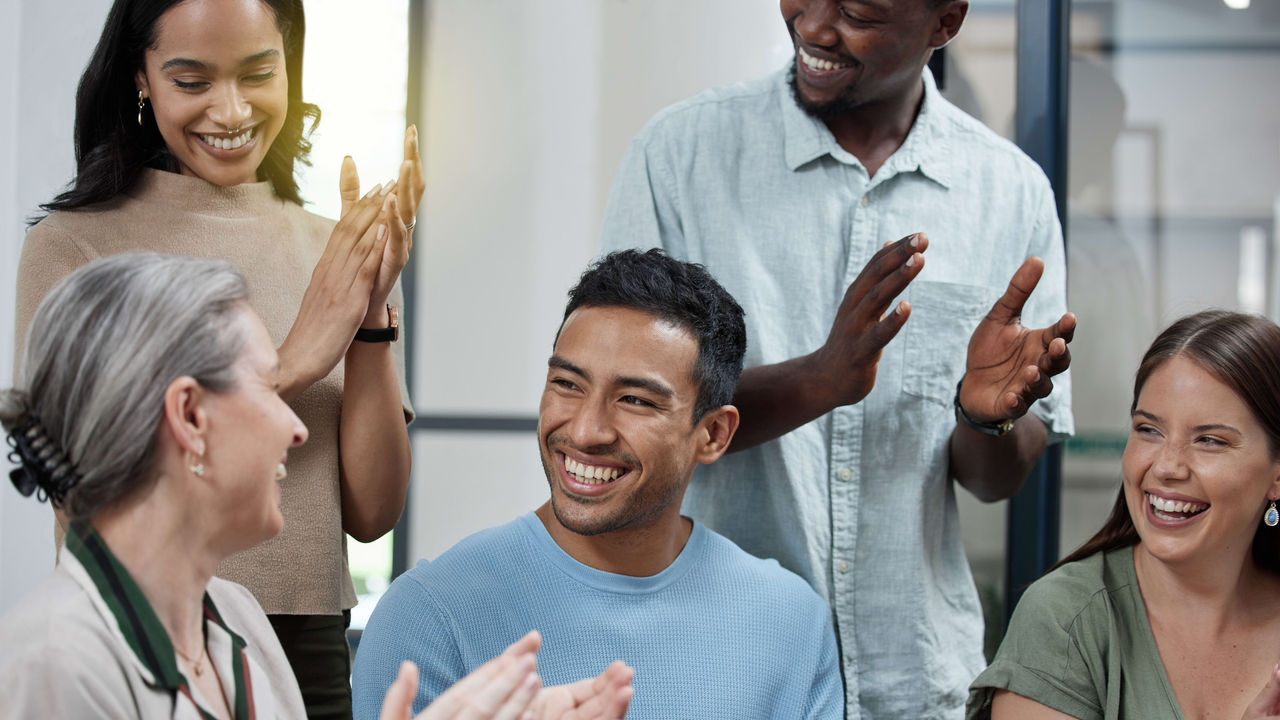 A group of people clapping together in an office.