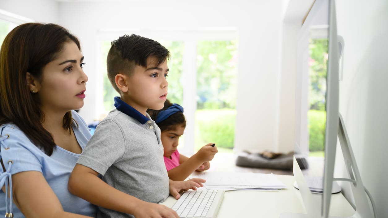 A woman and her son are using a computer at home.