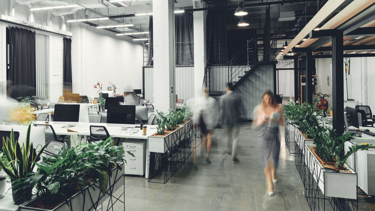 A blurry image of people walking in an office.