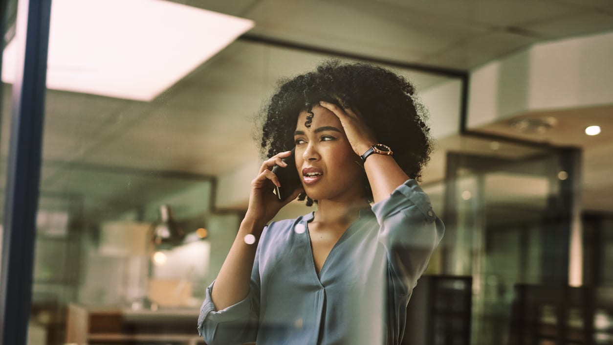 A woman talking on a cell phone in an office.