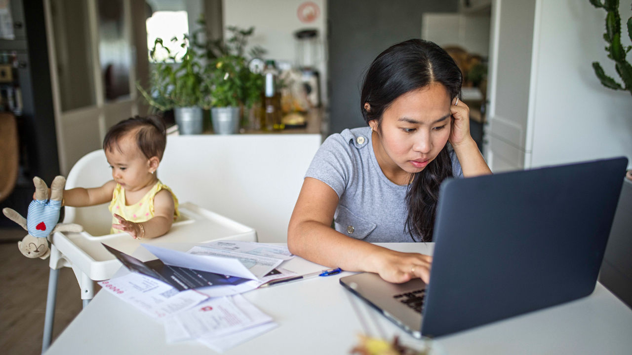 A woman sitting at a table with a baby and a laptop.