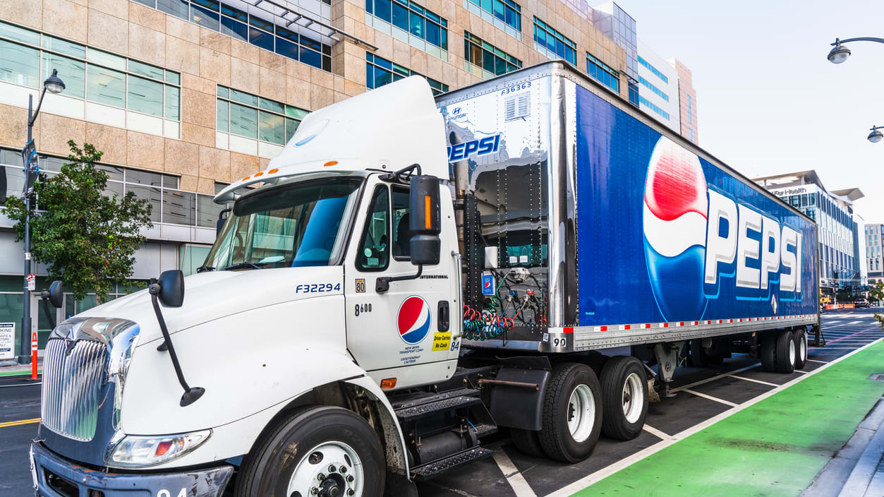A pepsi truck is driving down a city street.