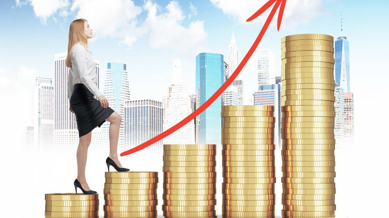 A business woman standing on top of stacks of gold coins.