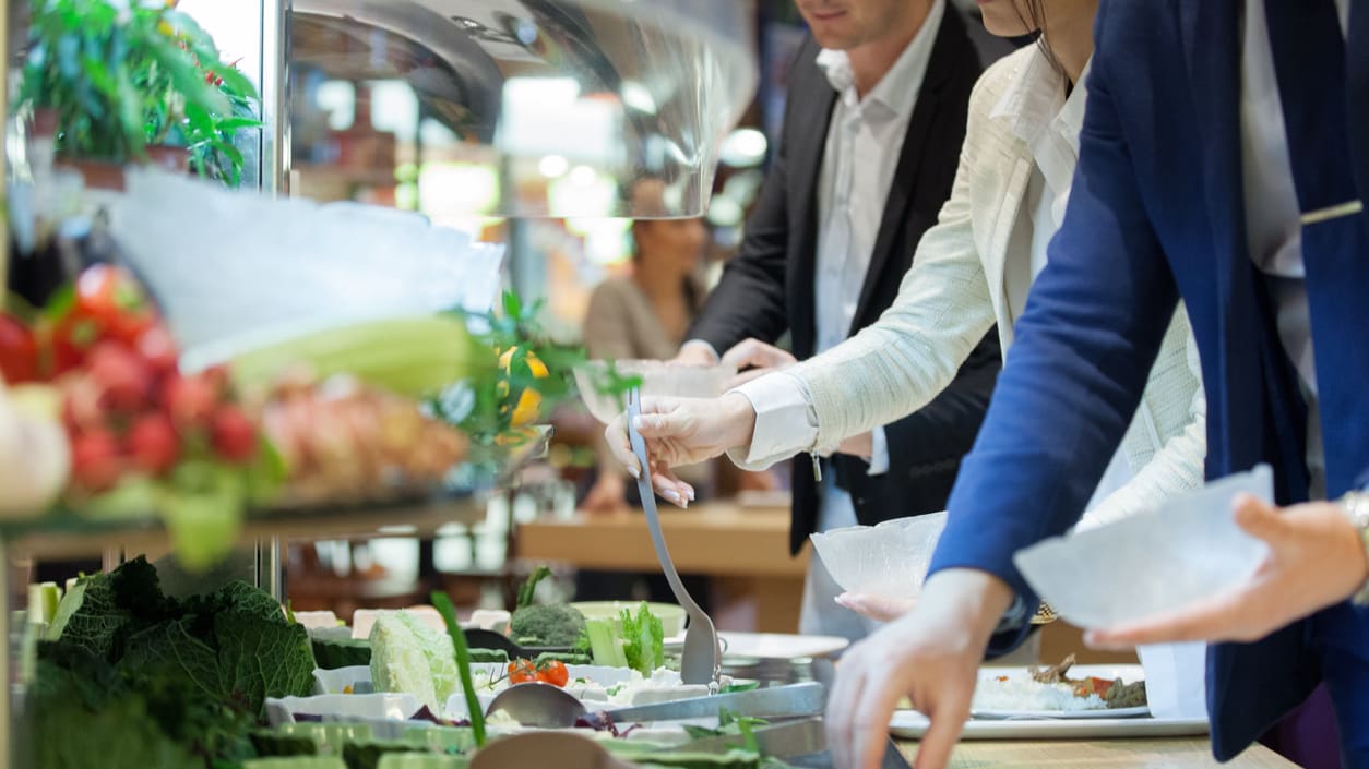 A group of people serving food at a buffet.