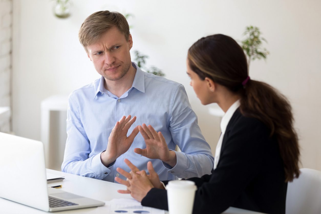Man looking skeptically at woman in an office setting.