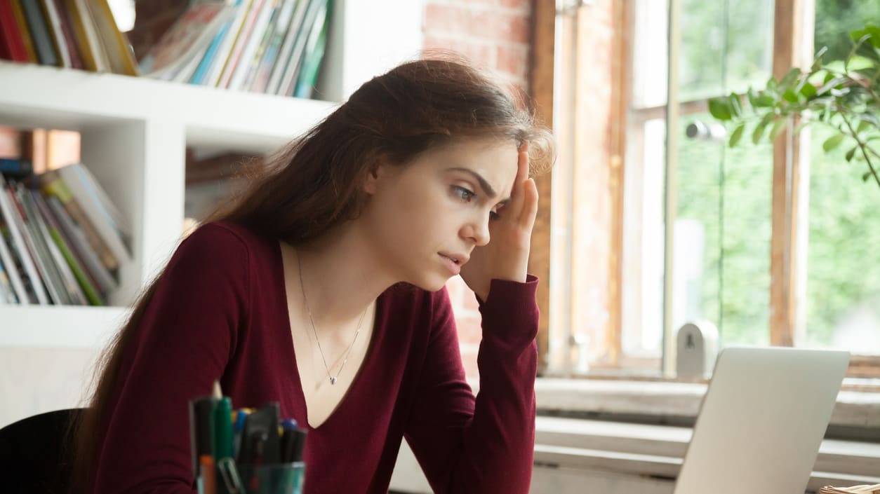 A woman sitting at a desk looking at her laptop.