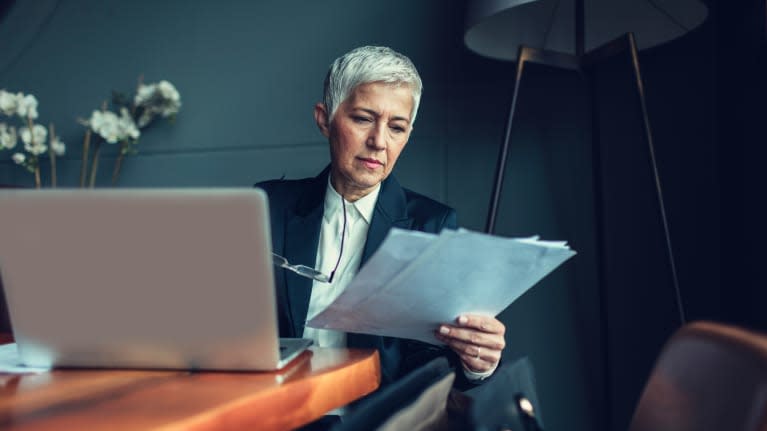 A woman is sitting at a table with a laptop in front of her.