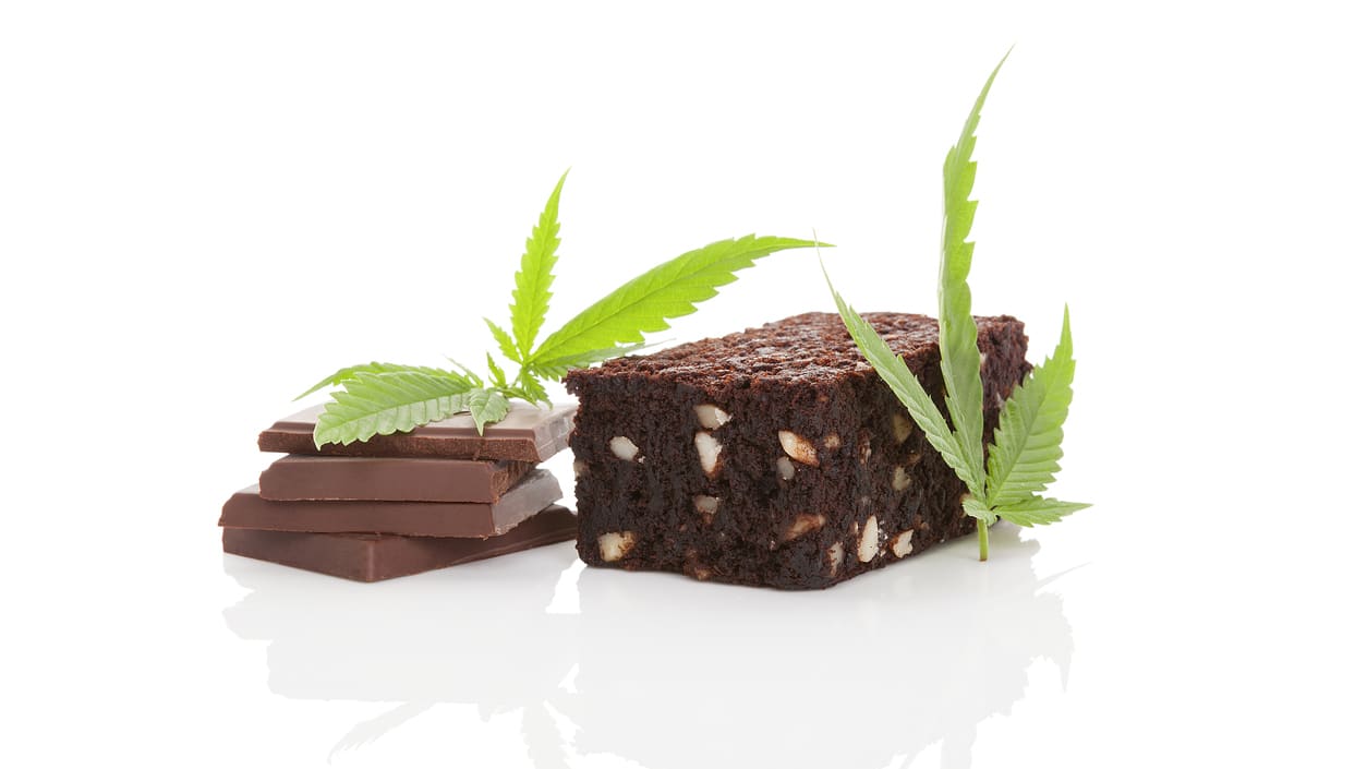 Chocolate brownie with cbd leaves on a white background.