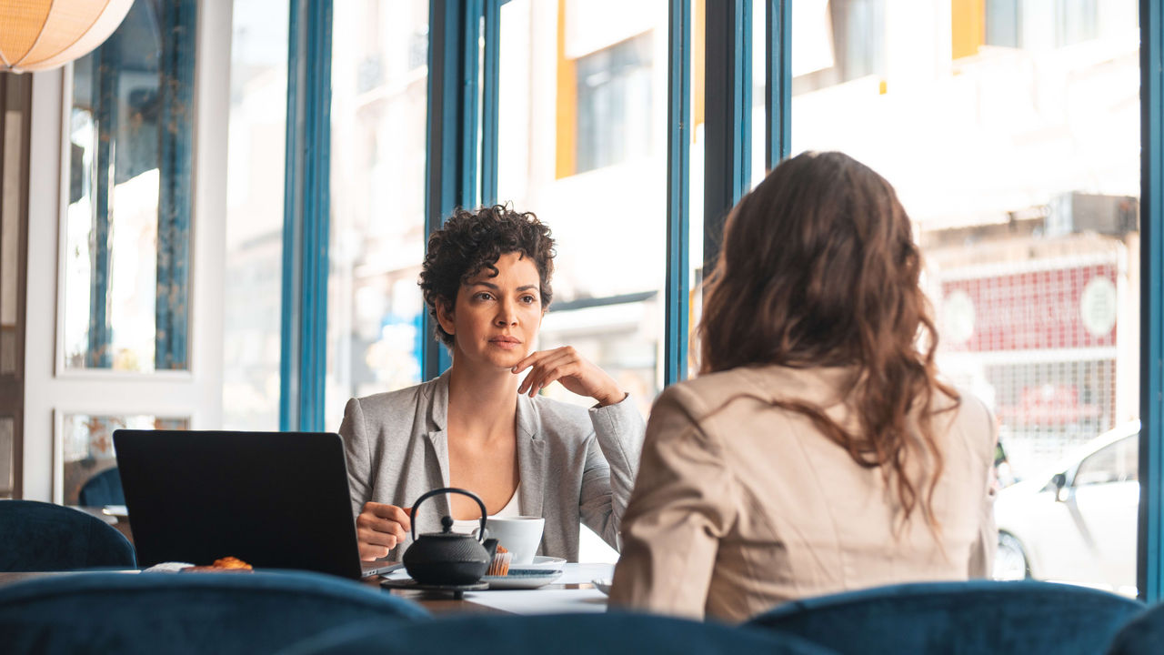 Two women having a conversation in a coffee shop.