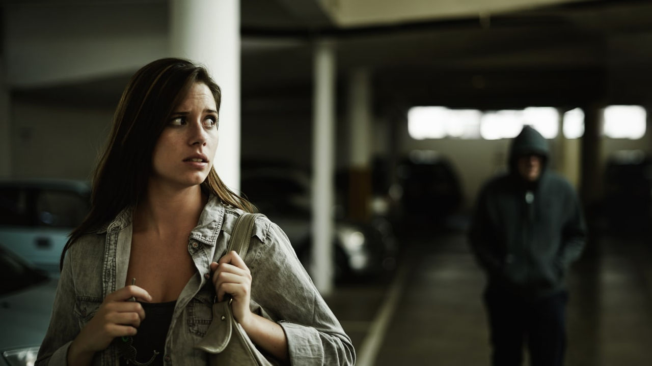 A woman in a hoodie is standing next to a man in a parking garage.