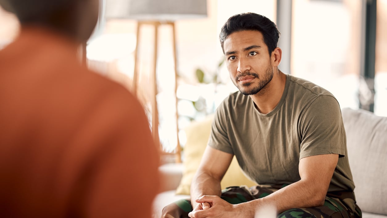 A man sitting on a couch talking to another man.