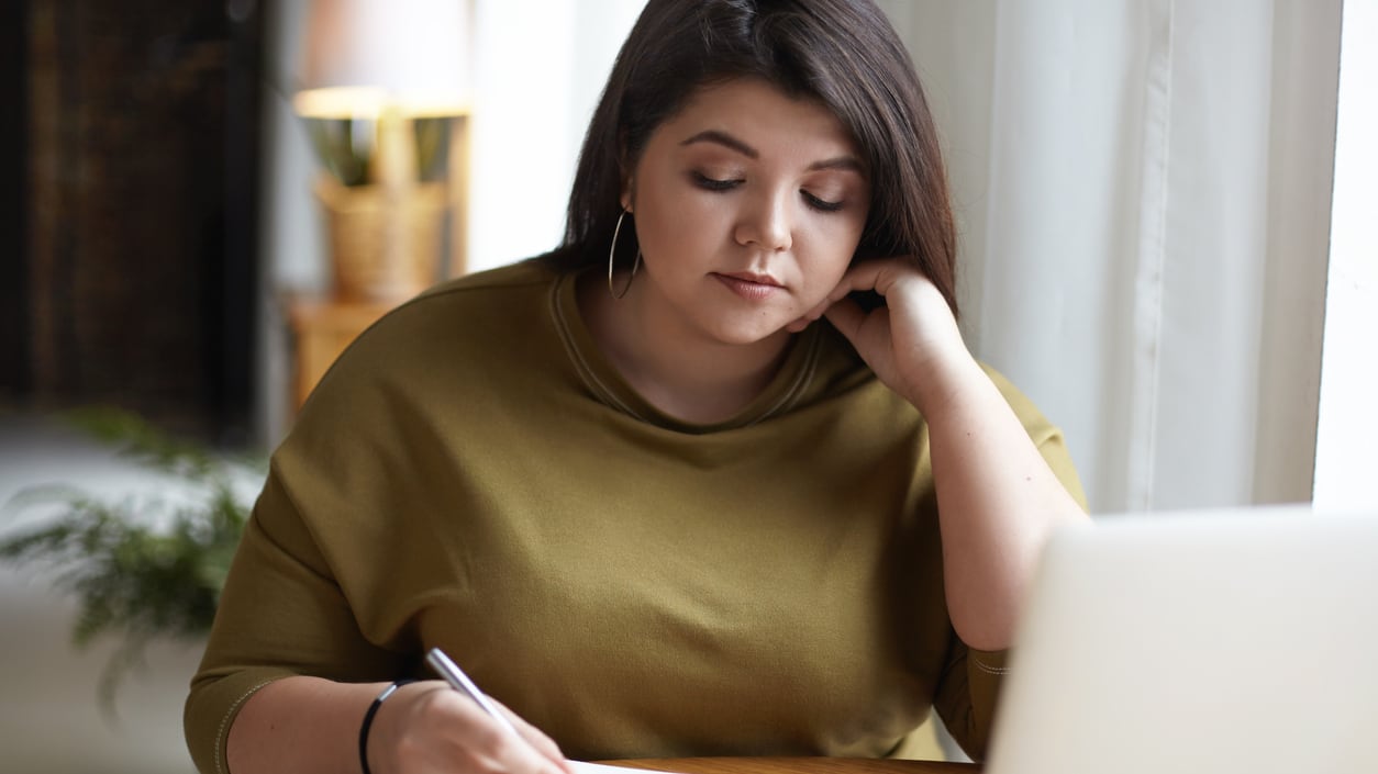 A woman sitting at a table with a laptop and a cup of coffee.