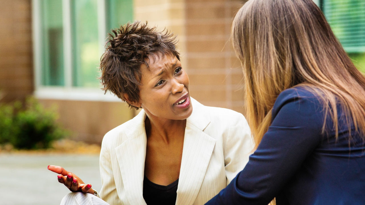 A woman is talking to another woman in a business suit.