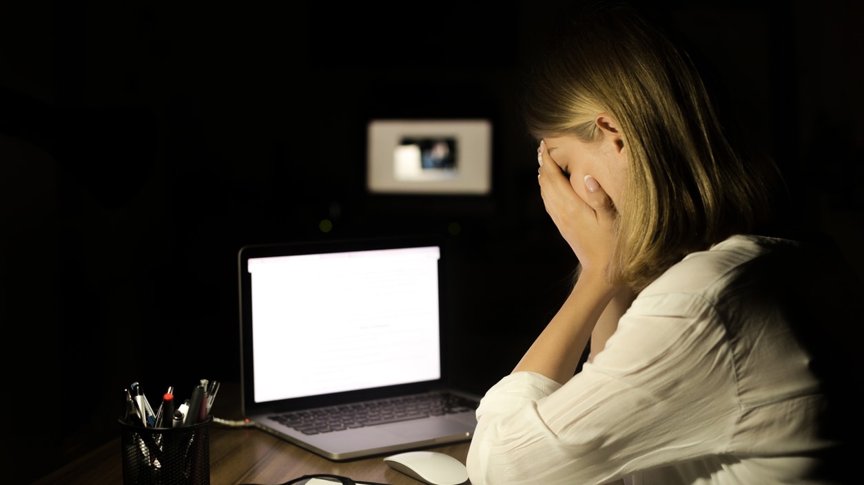 A woman is sitting at a desk with a laptop in front of her.