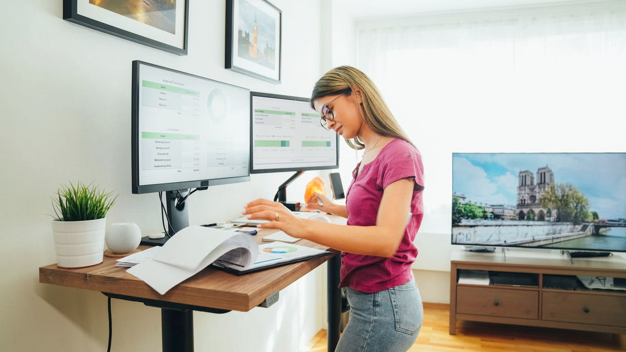 A woman working at a desk with two monitors.