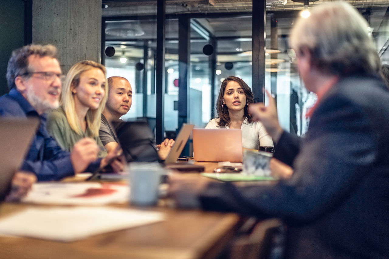 Multi-generation group of business people discussing ideas at a conference table in a modern office.