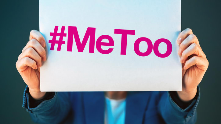 A woman holding up a paper with the word metoo on it.