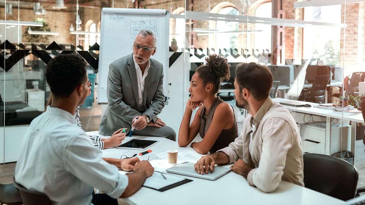 A group of people sitting around a table in an office.