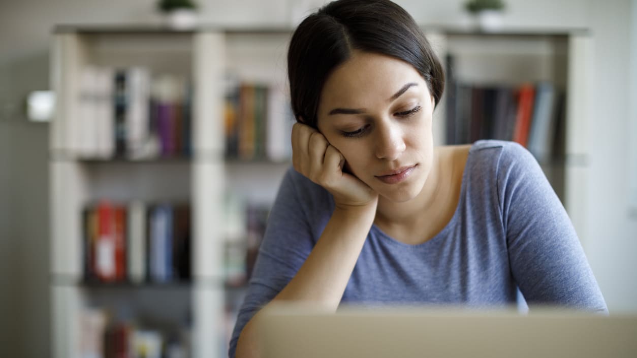 A woman is sitting at a desk with a laptop in front of her.