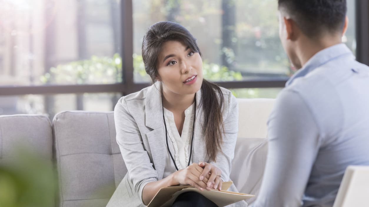 A man and woman sitting on a couch talking to each other.