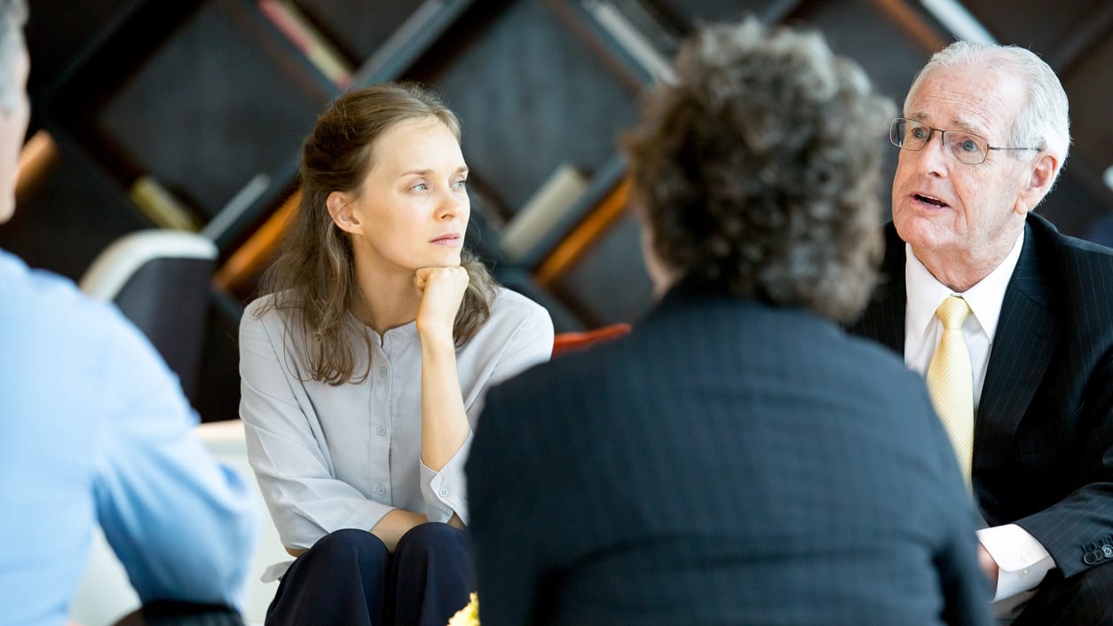 A group of people sitting around a table in a conference room.