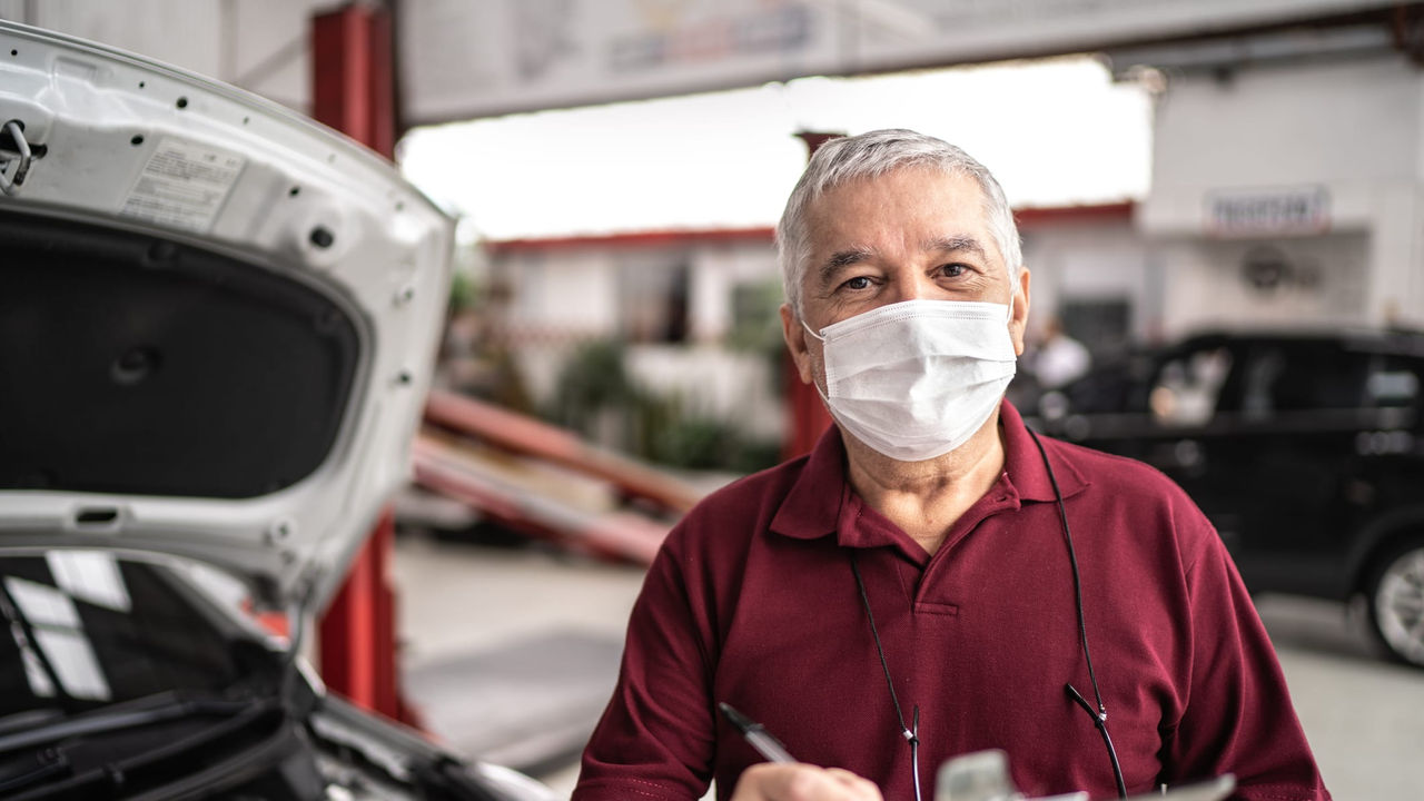 A man wearing a face mask in front of a car.