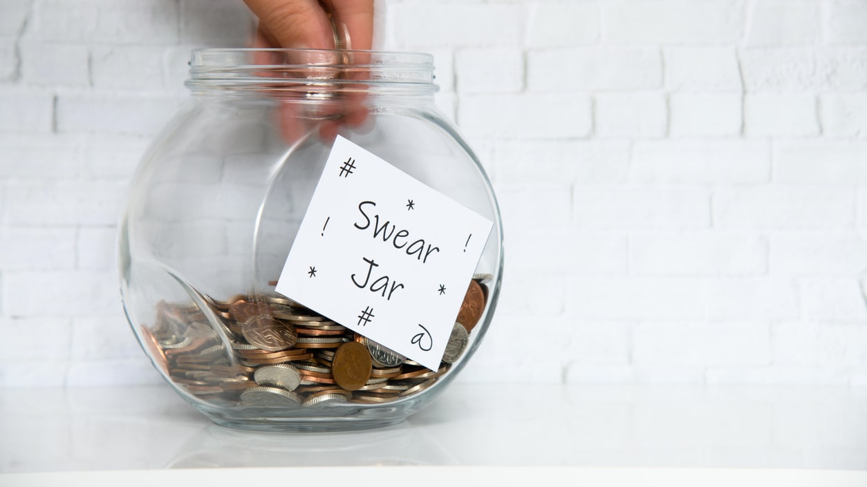 A person putting coins into a jar with a note on it.