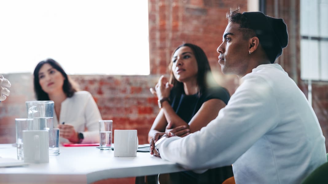 A group of people sitting around a table in a meeting.